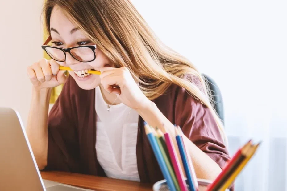woman biting a pencil in front of a laptop